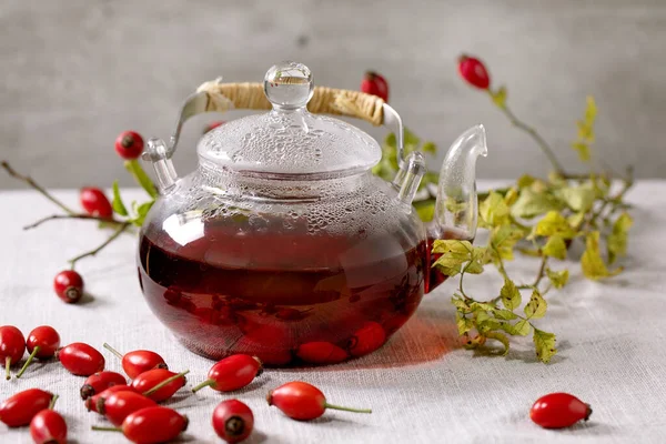 玫瑰山莓香草茶在玻璃杯茶壶站在白色亚麻布桌布上 周围是野的秋天浆果 健康的热饮 — 图库照片