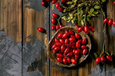 Seramik tabakta gül renkli böğürtlen ve eski ahşap arka planda yapraklar. Kış için sonbahar vitamin rezervleri. Düz yat, boşluğu kopyala