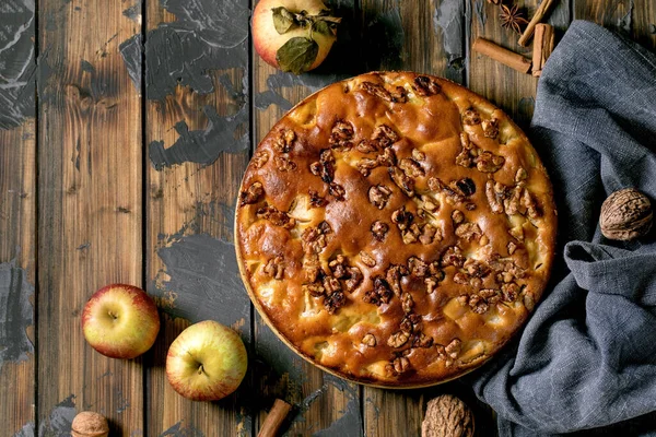 Ev yapımı elma ve cevizli kek Charlotte tabakta taze elma, tarçın ve fındıklı koyu ahşap arka planda. Sonbahar ev yapımı. Düz yat, boşluğu kopyala