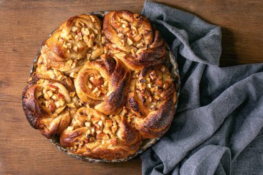 Elmalı tarçınlı çörekler ahşap arka planda keten bezle birlikte yuvarlak fırın tepsisinde duruyor. Geleneksel ev fırını. Düz yat, boşluğu kopyala