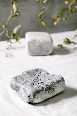 Geometrik kare taşların podyum ya da ürün sunumu için kaidesi ya da dal desenli beyaz tekstil sergisi olarak kullanıldığı soyut doğal sahne. Reklam için herhangi bir ürün gösterilecek sahne.