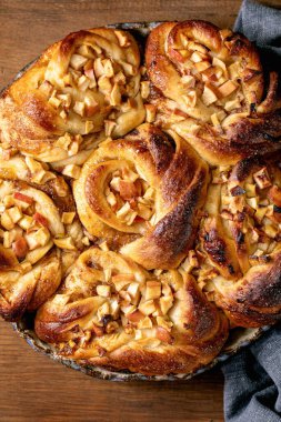 Elmalı tarçınlı çörekler ahşap arka planda keten bezle birlikte yuvarlak fırın tepsisinde duruyor. Geleneksel ev fırını. Düz yat, kapat.