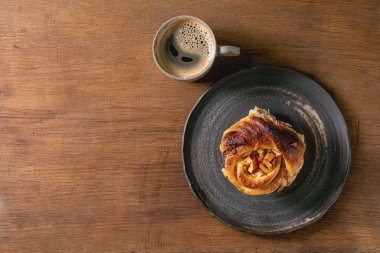 Elmalı tarçınlı çörek ve kahve fincanı tahta arka planda duruyor. Fırınla kahve molası. Düz yat, boşluğu kopyala
