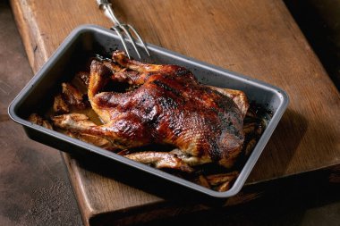 Geleneksel bayram yemeği kavrulmuş ördek. Elmalı ve ahşap masa üzerinde et çatalı olan fırın tepsisi..