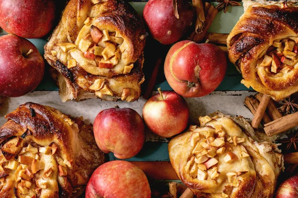 甜苹果粘肉桂卷面包与园艺苹果和肉桂棒在木制彩色托盘 传统的家庭烘焙 平躺在地上 — 图库照片