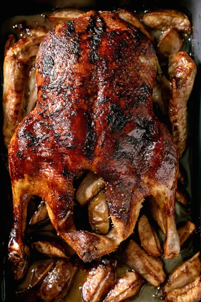 Classic holiday dish roasted glazed duck with apples in baking tray. Top view, close-up