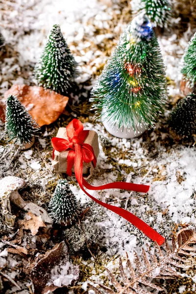 圣诞或新年贺卡 礼品盒内装有红丝带的手工纸盒 雪地覆盖着苔藓 点缀着装饰精美的圣诞树 圣诞节的节日气氛 高角度视图 — 图库照片