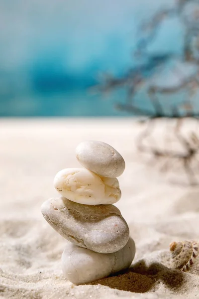 여름의 모래사장에서 파도와 껍질로 균형을 위하여 가지하얀 매끄러운 돌들을 쌓는다 — 스톡 사진
