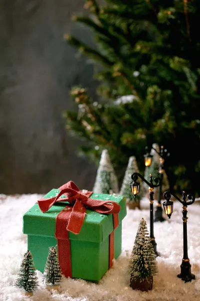 クリスマスや新年の挨拶カード おもちゃの街路灯 背景に雪やモミの木の周りの装飾的なクリスマスツリーと大きな緑のギフトボックス クリスマス休暇の雰囲気 — ストック写真