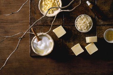 Ev yapımı organik kozmetik malzemeleri. Yüz kremi sürüyor, sabun, temel yağlar, kakao yağı, seramik kaseler içinde kuru dallı koyu fayanslar. Çevre dostu arama. Düz yatıyordu