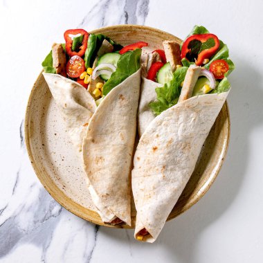 Beyaz mermer arka planda seramik tabakta domuz eti ve sebzeli geleneksel Meksika tortila dürümü. Üst manzara, düz yatış. Ev yapımı fast food. Kare resim