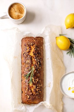Ev yapımı limonlu kek, fındıklı ve biberiyeli, buruşuk kabartma kağıdında taze limon, beyaz sos ve beyaz mermer masada kahve fincanı ile servis ediliyor. Düz yatıyordu