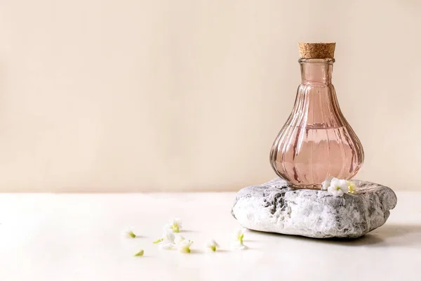 小さな白い花と白い大理石のテーブルの上にテクスチャ石の上に立ってコルクで香水の美しいピンクの透明ボトルKalancoe周り 香水は デザインラベルのための場所と概念を作る — ストック写真