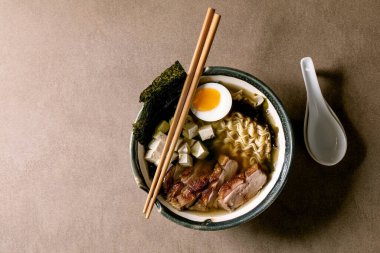 Erişteli Asya usulü ramen, ızgara ördek göğsü, tofu, deniz yosunu nori cipsi ve kaşık kaşık kahverengi desenli seramik kasede haşlanmış yumurta. Düz yat, boşluğu kopyala