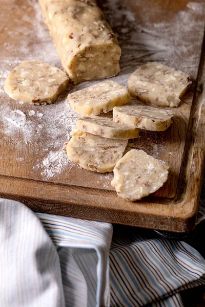 在深色木桌上的木制切菜板上 用坚果和白巧克力切自制的小面包面团来烹调糖饼干 家常便饭 — 图库照片