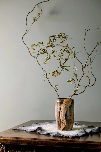 家庭内部 米色手工制作的陶瓷花瓶中的干枝枝干矗立在后面有灰色墙壁的古董木桌上 复制空间 — 图库照片