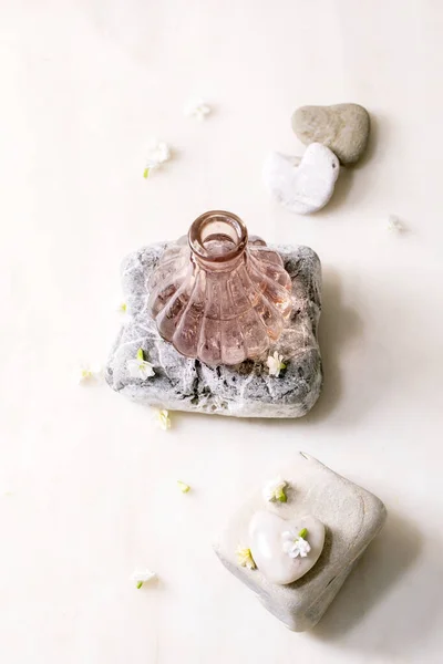 美しいピンクの透明香水のボトルを開いた 白い大理石のテーブルの上にテクスチャの石の上に小さな白い花Kalancoeの周りに立っている 香水は デザインラベルのための場所と概念を作る — ストック写真