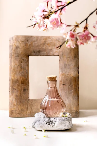 玻璃粉透明瓶的香水与软木塞 站在白色大理石桌上的纹理石头上 白色的花和春天的枝条 用于设计标签的香水制造概念 — 图库照片