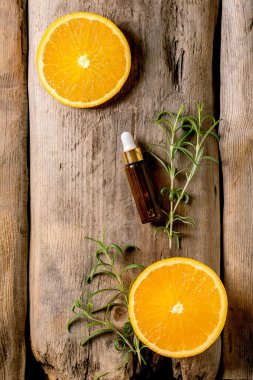 Biberiye ve portakal aromalı organik malzeme ya da cam şişedeki pipetli taze malzemelerden kozmetik yağ. Cilt bakımı antistres etkisi için tanıtım konsepti. Eski tahta arkaplan.