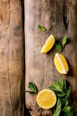 Citrus ve şifalı bitkiler. Eski ahşap zemin üzerinde taze organik dilimlenmiş limon ve nane dalları. Üst görünüm, alanı kopyala