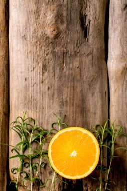 Citrus ve şifalı bitkiler. Eski ahşap zemin üzerinde taze organik dilimlenmiş portakal ve biberiye dalları. Üst görünüm, alanı kopyala