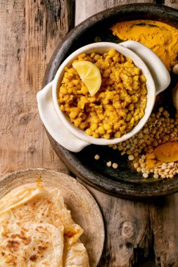 Dhal ve roti ekmeği. Geleneksel Hint sarısı bezelye dalıyla Roti yassı ekmek, eski ahşap masada seramik kasede limonla servis ediliyor. Düz yat, boşluğu kopyala