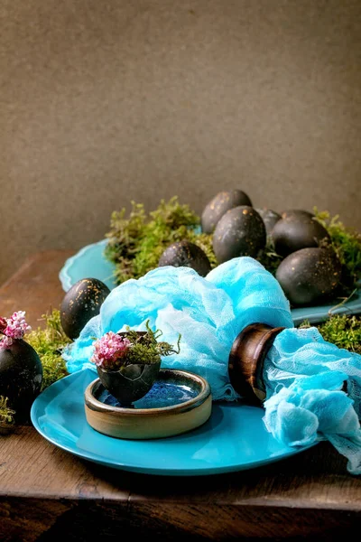 复活节餐桌设置与空绿松石陶瓷盘 装饰森林苔藓 黑色彩蛋和粉红色春天花壳在木制桌子上 时尚的春假 — 图库照片