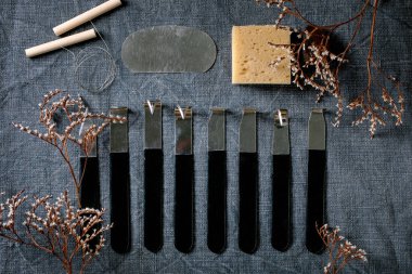 Çömlek hobisi için hazır. Çiğ gri kil ve çanak çömlek seramik aletleri, mavi keten kumaş kumaş ve kuru çiçeklerle sıralanmış. Üst Manzara. DIY çömlekçi hobisi