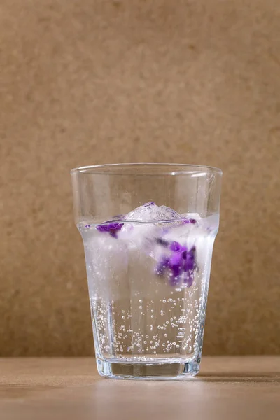 Przezroczysta Szklanka Musującej Sody Fiołkami Kostki Lodu Kwiat Produkcji Zimnego — Zdjęcie stockowe