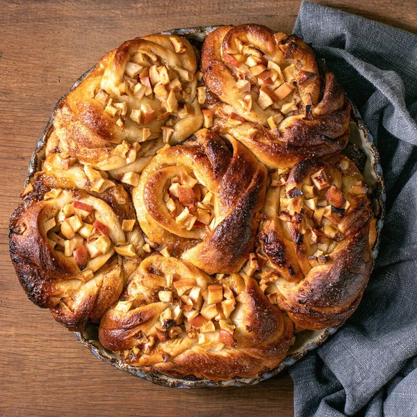 Elmalı tarçınlı çörekler ahşap arka planda keten bezle birlikte yuvarlak fırın tepsisinde duruyor. Geleneksel ev fırını. Düz konum, kopyalama alanı. Kare resim