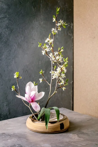 春天Ikebana 花的构图 春花开的木兰花和李枝花在褐色陶瓷碗里 屹立在灰色的桌子上 日本风格的家居装饰 复制空间 — 图库照片
