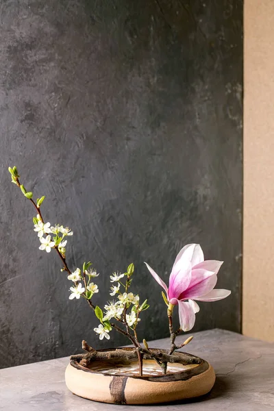 春天Ikebana 花的构图 春花开的木兰花和李枝花在褐色陶瓷碗里 屹立在灰色的桌子上 日本风格的家居装饰 复制空间 — 图库照片