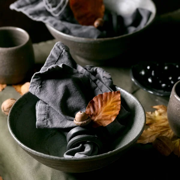简朴的秋天万圣节或感恩节餐桌设置与空手工陶瓷餐具 灰色粗糙碗和杯子亚麻布桌布黄叶和橡木 黑暗的背景正方形图像 — 图库照片