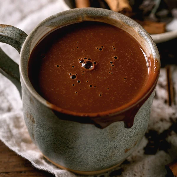 一杯辛辣的自制巧克力 配上切碎的黑巧克力和肉桂在亚麻布餐巾上 关上温暖舒适的饮料 正方形图像 — 图库照片