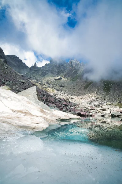 小さな高山湖と初夏の最後の雪と山の風景 — ストック写真