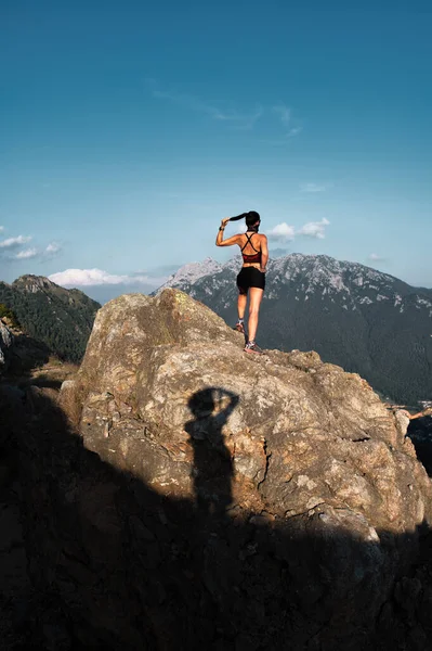 Shadow of a photographer portraying a sportswoman on a rock in the mountains