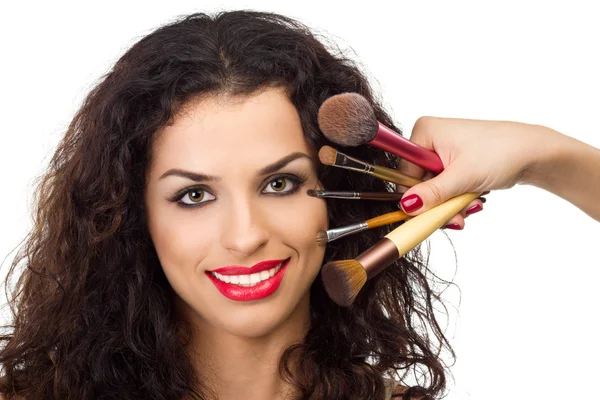 Mulher sorridente bonita com pincéis de maquiagem perto de seu rosto — Fotografia de Stock