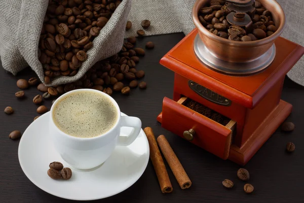 En kopp kaffe nær brente kaffebønner og en kaffekvern. – stockfoto