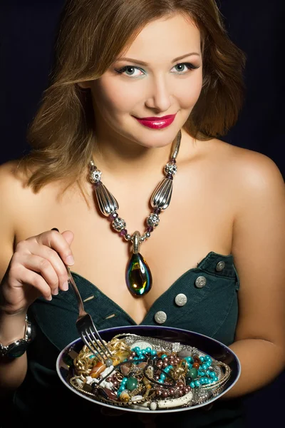Young woman holding fork and plate with jewelry — Stock Photo, Image
