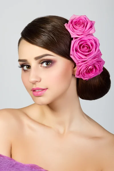 Bella giovane donna con rose rosa nei capelli — Foto Stock