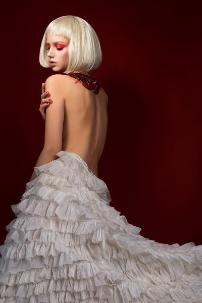 Молодая чувственная женщина в белой юбке на красном фоне
