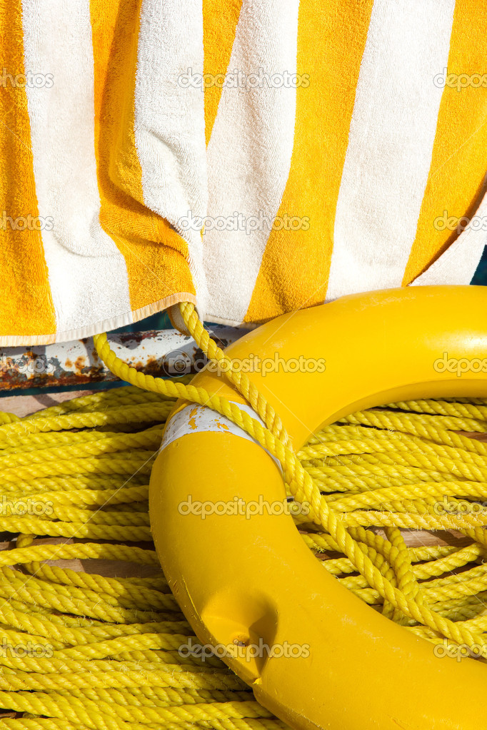 Yellow life buoy, rope and towel on a pier