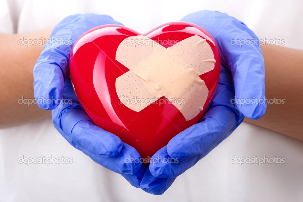 Doctor's hands in blue gloves holding plastered heart