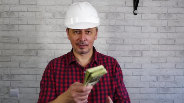 Portré egy vidám férfiról egy építkezési sisakban, aki pénzt dob. . — Stock videók