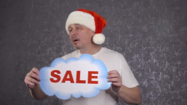 A man in a Santa Claus hat offers a sale. — Stock Video