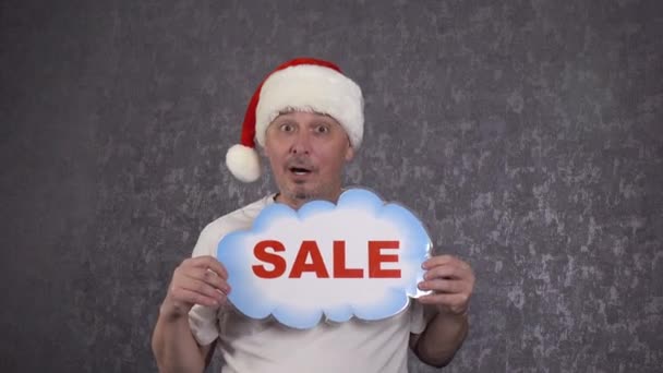 Mężczyzna w kapeluszu Świętego Mikołaja oferuje sprzedaż.. — Wideo stockowe