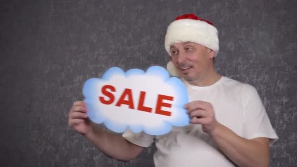 A man in a Santa Claus hat offers a sale. — Stock Video