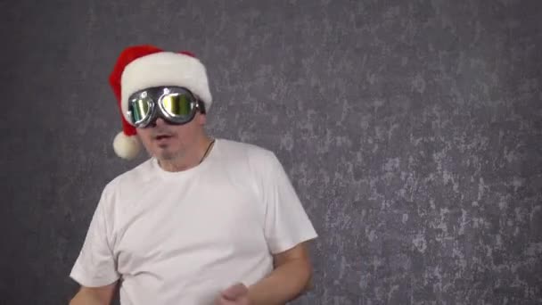 Mężczyzna w kapeluszu Świętego Mikołaja śmiesznie tańczy.. — Wideo stockowe