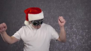 Noel Baba şapkalı bir adam komik dans ediyor..