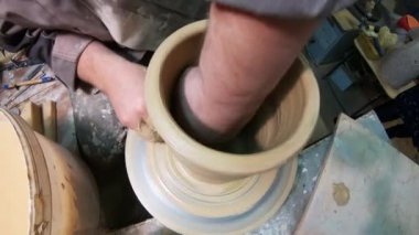 A male potter on a potters wheel makes a ceramic jug of clay.